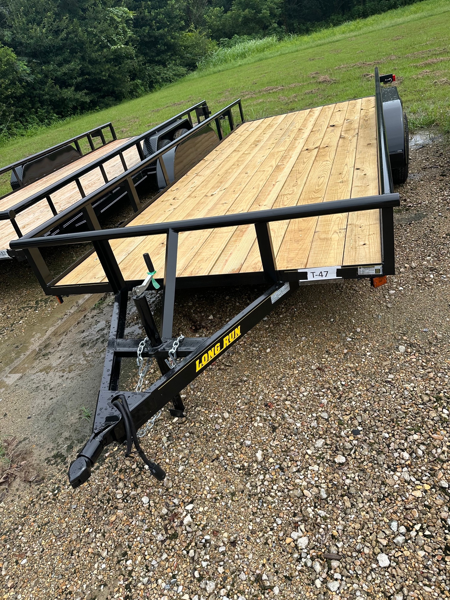 Long Run tandem axle utility trailer with slide ramps on gravel lot